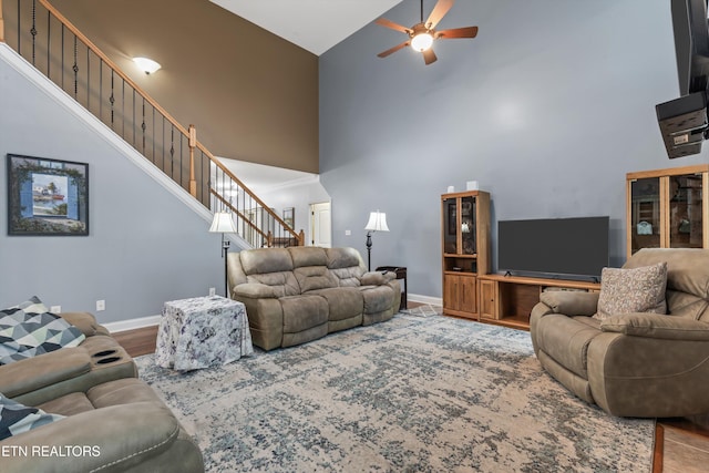 living area featuring stairway, high vaulted ceiling, baseboards, and a ceiling fan