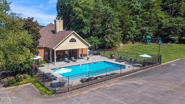 view of swimming pool featuring a lawn, fence, a patio area, and a fenced in pool