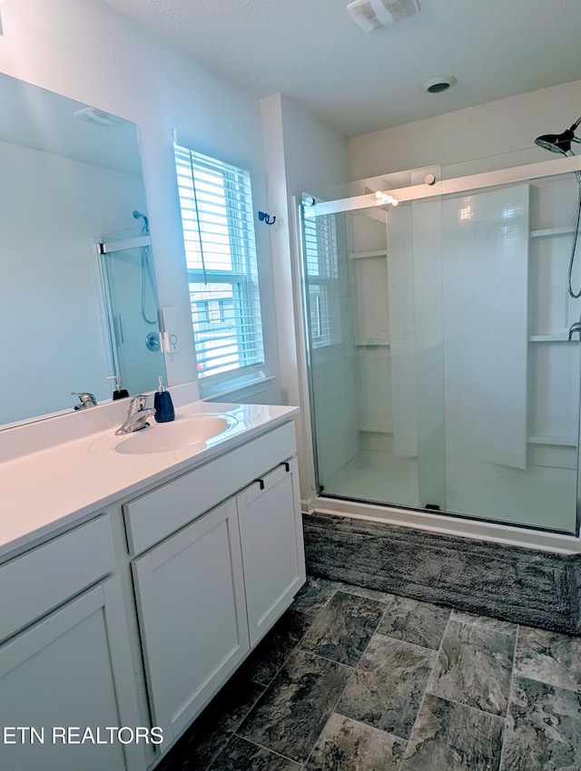 full bathroom with vanity, a shower stall, and visible vents