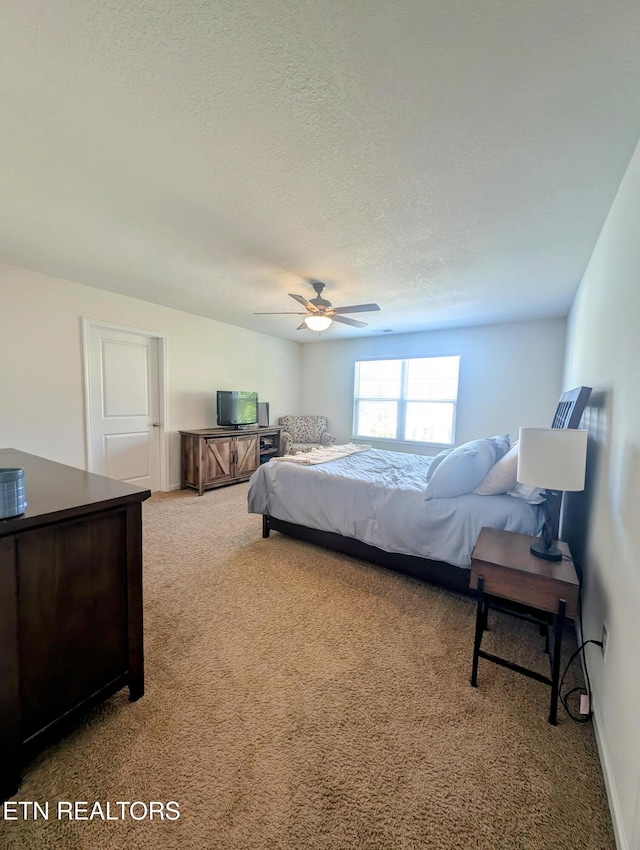 carpeted bedroom featuring a ceiling fan, baseboards, and a textured ceiling