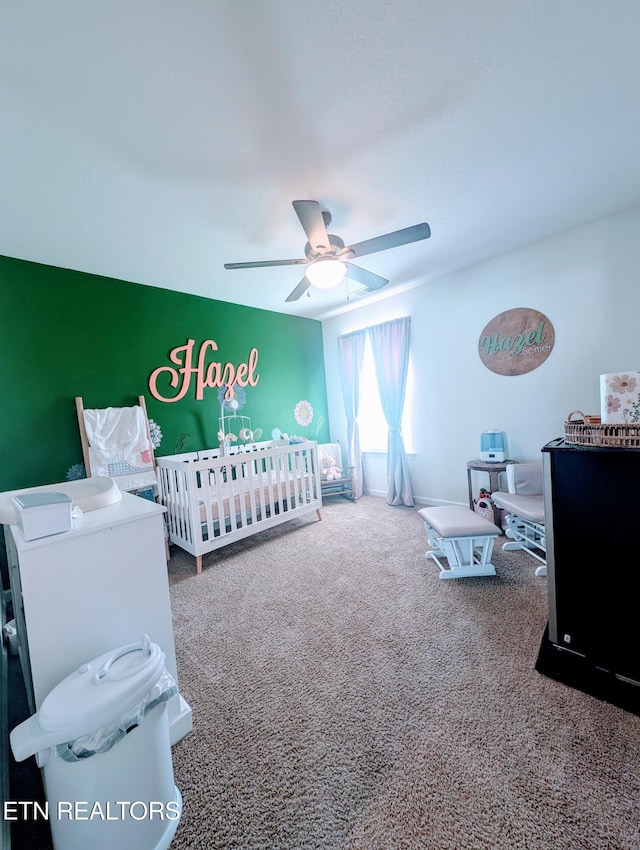 bedroom featuring ceiling fan, carpet, and a nursery area