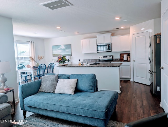 living area featuring dark wood-type flooring, visible vents, and recessed lighting