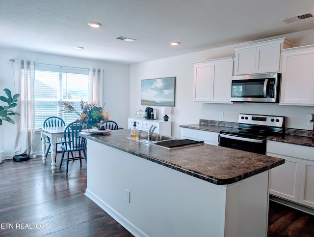 kitchen featuring dark countertops, appliances with stainless steel finishes, visible vents, and white cabinetry