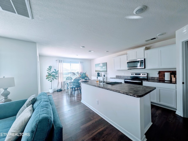 kitchen featuring a textured ceiling, stainless steel appliances, visible vents, and dark wood-style floors