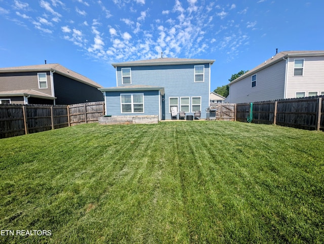 back of house featuring a yard and a fenced backyard