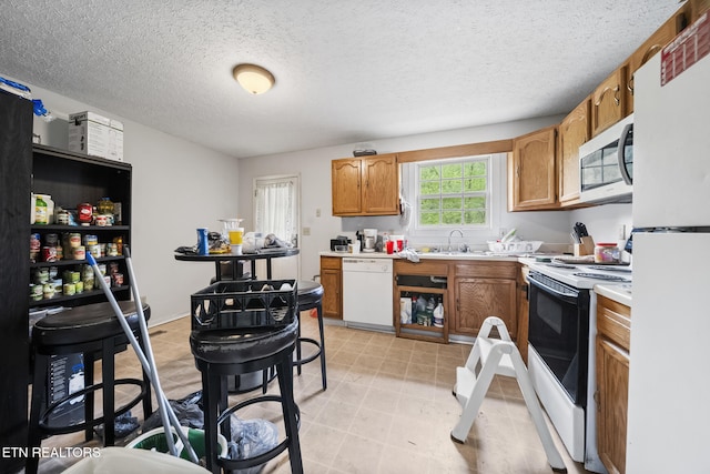 301 Hill St, Rocky Top, TN 37769 - kitchen with a textured ceiling, a sink, light countertops, white appliances, and brown cabinetry