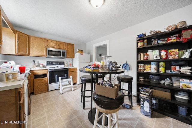 301 Hill St, Rocky Top, TN 37769 - kitchen with white appliances, a textured ceiling, light countertops, and brown cabinets