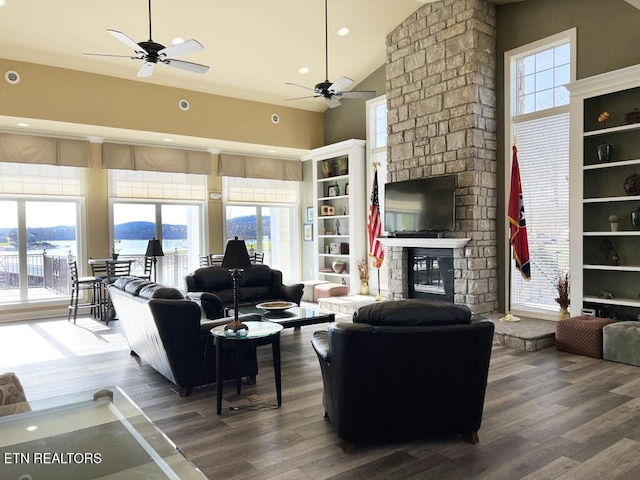 living area featuring ceiling fan, a brick fireplace, high vaulted ceiling, and wood finished floors