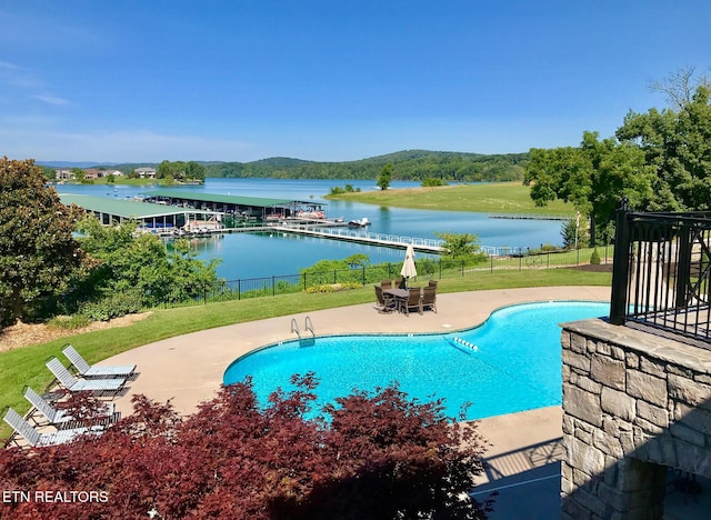view of swimming pool with a patio area, a water view, fence, and a fenced in pool