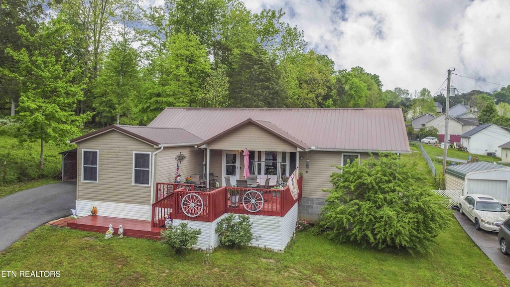 manufactured / mobile home with driveway, covered porch, a front yard, and metal roof