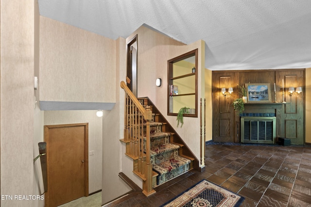 stairway with a textured ceiling and a glass covered fireplace