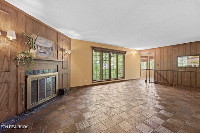 unfurnished living room with wooden walls, baseboards, and a fireplace with flush hearth