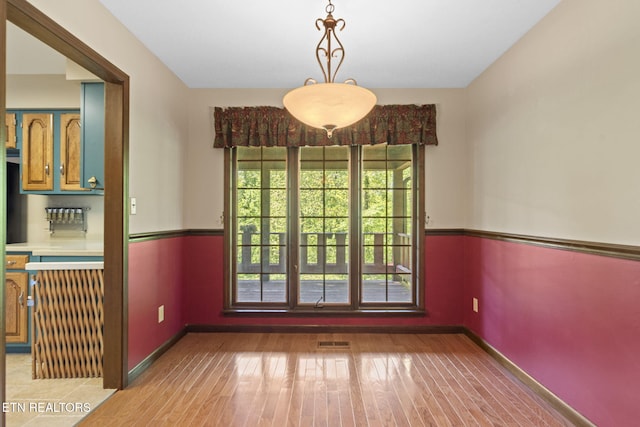 unfurnished dining area featuring baseboards, visible vents, and light wood-style floors