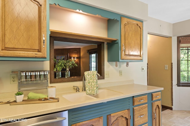 kitchen featuring stainless steel dishwasher, a sink, and light countertops
