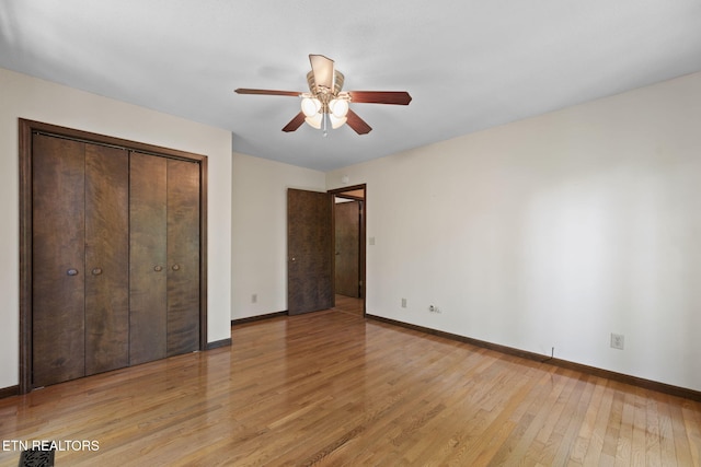unfurnished bedroom featuring light wood-type flooring, a ceiling fan, baseboards, and a closet