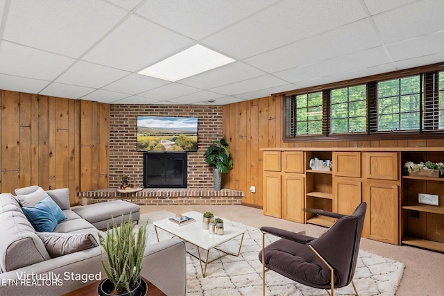 living area with wooden walls, light colored carpet, and a drop ceiling