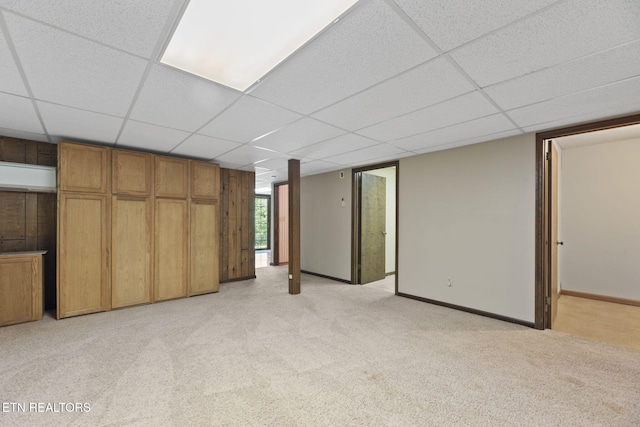 unfurnished bedroom with baseboards, light colored carpet, and a drop ceiling