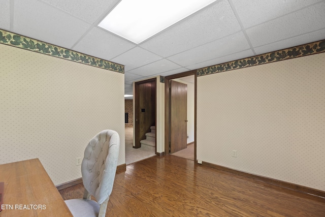 office area with baseboards, a drop ceiling, and wood finished floors