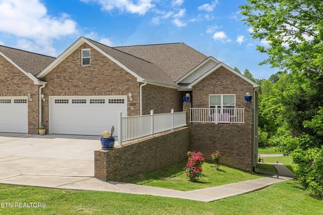 craftsman house featuring a garage, a front lawn, brick siding, a shingled roof, and driveway