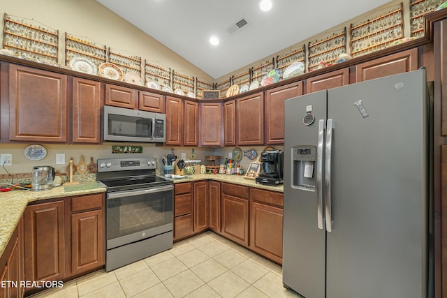 kitchen featuring appliances with stainless steel finishes, light stone counters, light tile patterned floors, lofted ceiling, and visible vents