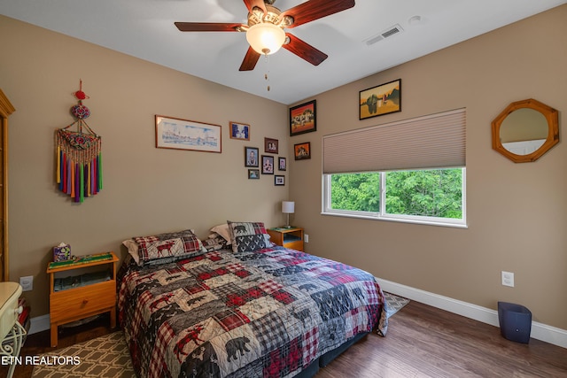 bedroom with baseboards, ceiling fan, wood finished floors, and visible vents