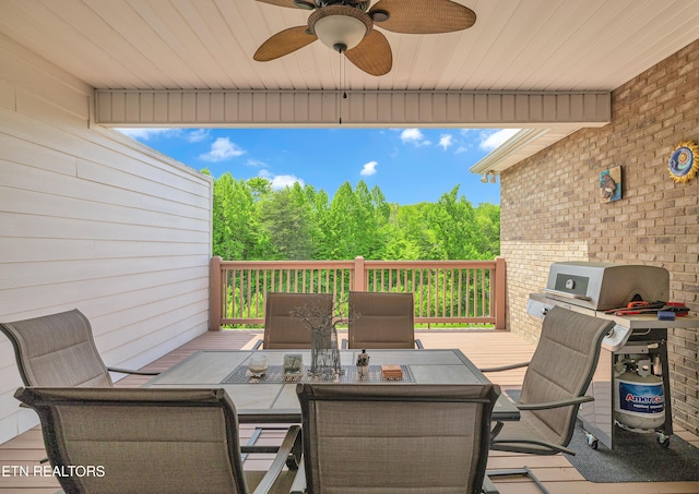 wooden deck with a ceiling fan, a forest view, area for grilling, and outdoor dining space