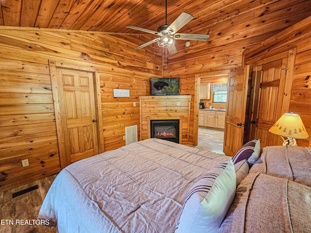 bedroom featuring connected bathroom, light wood-style flooring, wood ceiling, wooden walls, and lofted ceiling
