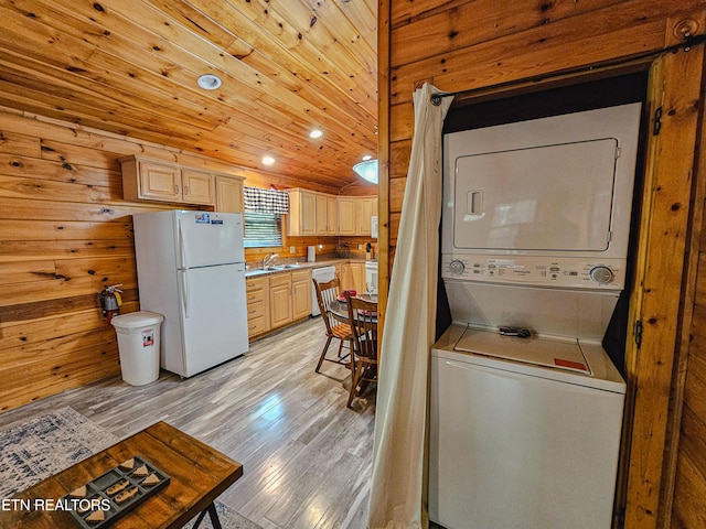 clothes washing area featuring stacked washer and dryer, recessed lighting, a sink, and light wood-style flooring