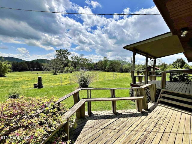 deck featuring fence, a rural view, a yard, and a mountain view