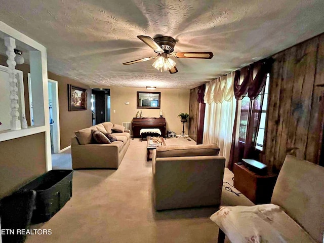 living area featuring a ceiling fan, carpet flooring, and a textured ceiling
