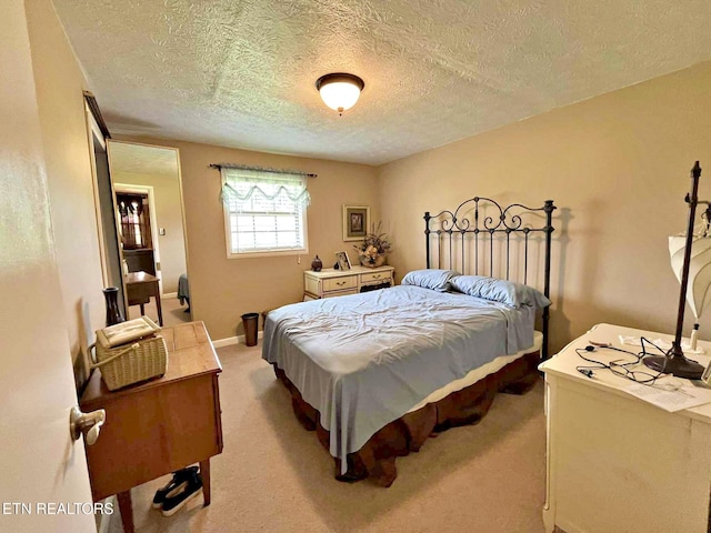 bedroom featuring a textured ceiling, carpet flooring, and baseboards