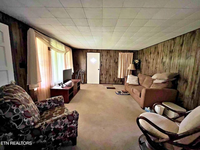 carpeted living room with wood walls