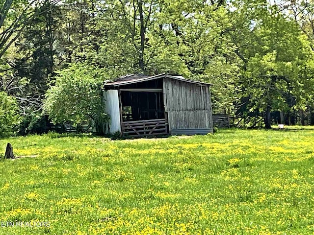 view of pole building with a yard and a view of trees