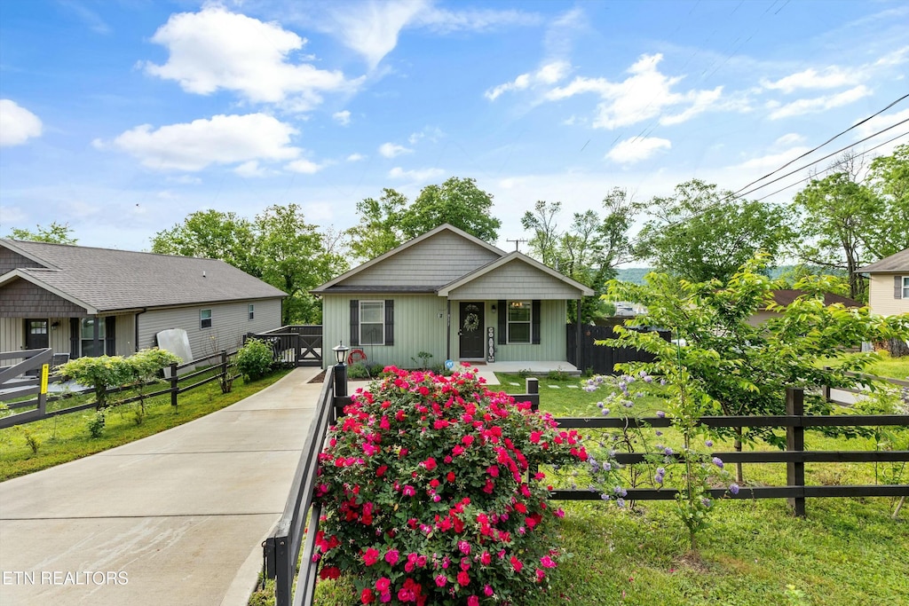 bungalow featuring a porch, fence, driveway, and a front lawn