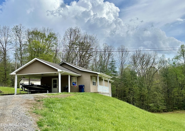 ranch-style house featuring a front lawn, gravel driveway, and a carport