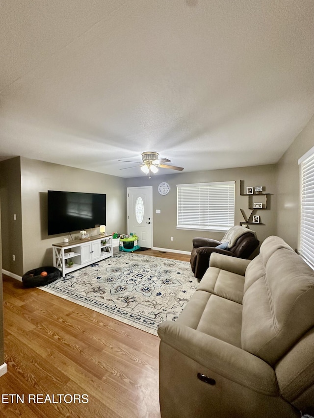 living area featuring baseboards, ceiling fan, and wood finished floors