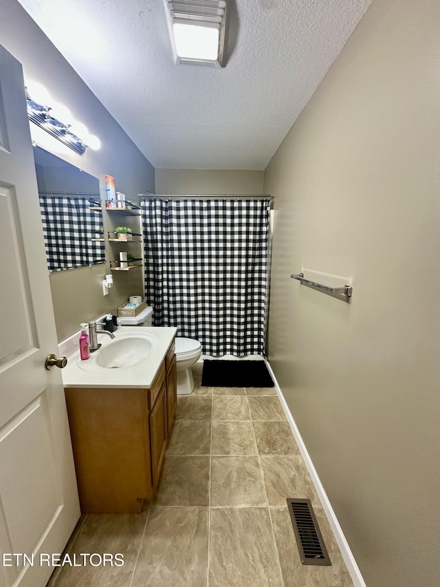 bathroom featuring visible vents, vanity, toilet, a textured ceiling, and tile patterned floors
