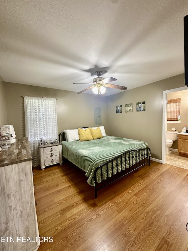 bedroom featuring a textured ceiling, a ceiling fan, ensuite bath, and wood finished floors