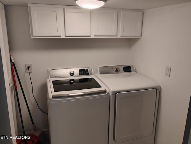 laundry area with independent washer and dryer and cabinet space