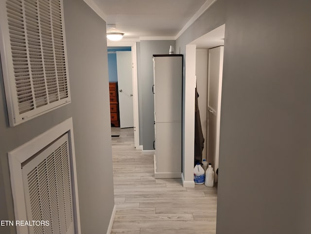 hallway with baseboards, light wood-style floors, visible vents, and ornamental molding