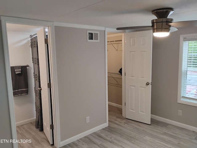 unfurnished bedroom featuring light wood-style floors, visible vents, baseboards, and a spacious closet