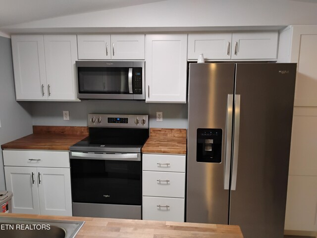 kitchen with white cabinets, appliances with stainless steel finishes, lofted ceiling, and butcher block countertops