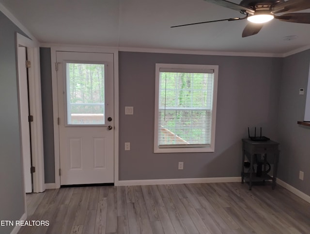 foyer entrance with crown molding, light wood-type flooring, baseboards, and ceiling fan