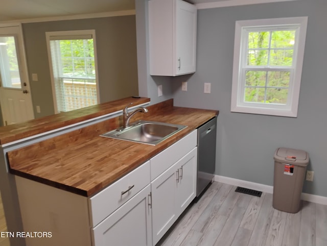 kitchen with stainless steel dishwasher, light wood-style floors, butcher block countertops, and a sink