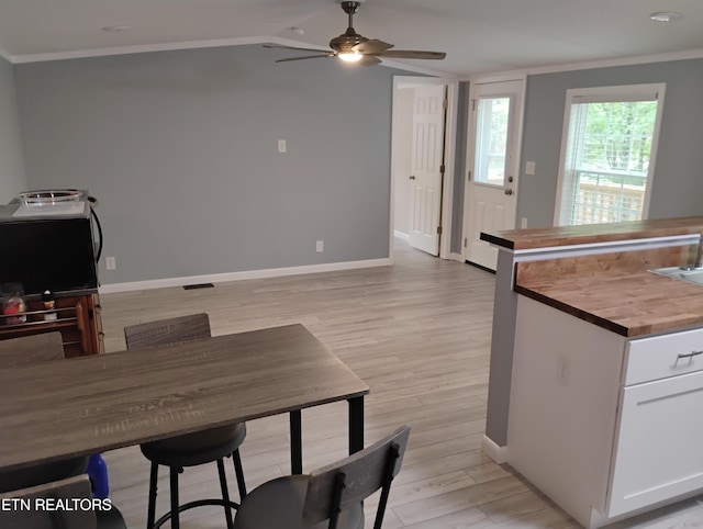 kitchen with a ceiling fan, wood counters, crown molding, light wood-type flooring, and white cabinetry