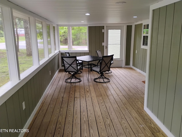 sunroom with a deck, outdoor dining area, and hardwood / wood-style flooring