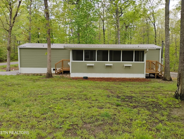 back of property featuring a yard, a sunroom, and metal roof