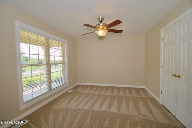 carpeted empty room with baseboards and ceiling fan