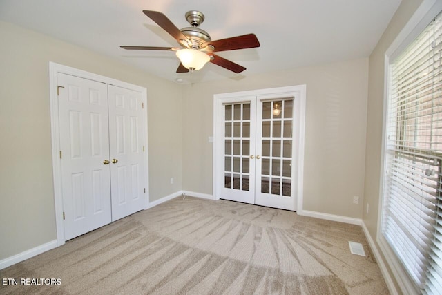 unfurnished bedroom with a closet, carpet floors, baseboards, and french doors