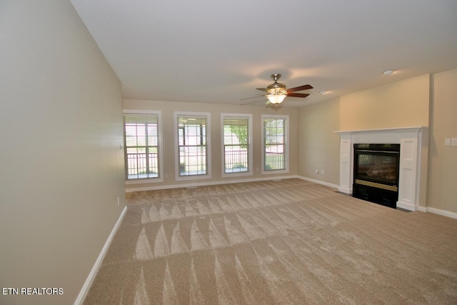 unfurnished living room with a ceiling fan, baseboards, a fireplace with flush hearth, and light carpet